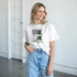 Grapes Graphic T-Shirt on a woman in a white cotton-blend tee with a grape print.