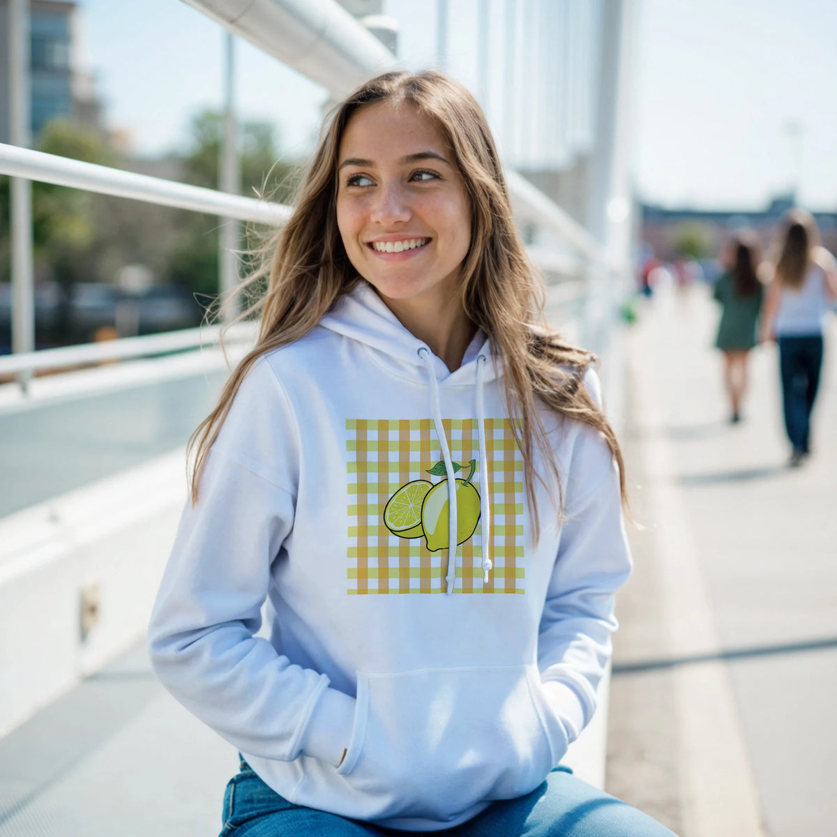 Smiling woman wearing a light-blue Retro Lemon Gingham Hoodie with a lemon graphic on yellow gingham.