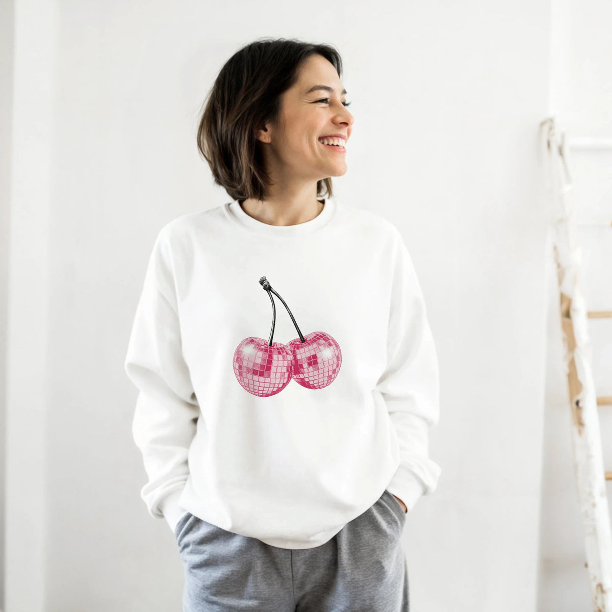 Pastel Y2K Cherries Sweatshirt with glitter pink cherry graphic, Urban Palm Trees, worn by a smiling woman.