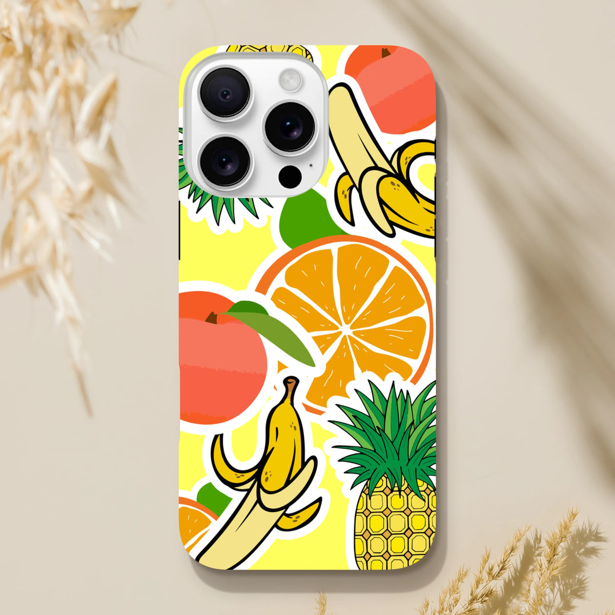 Yellow iPhone case featuring bold orange, banana, and pineapple sticker graphics on a bright background.