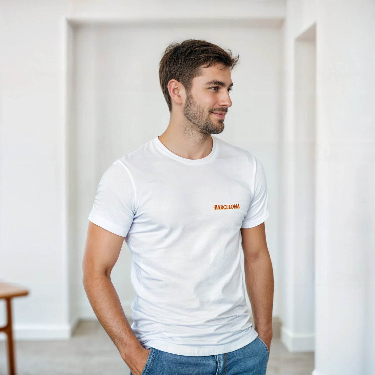 Man wearing a white Barcelona Spain graphic T-shirt with orange 'BARCELONA' text, casual indoor setting.
