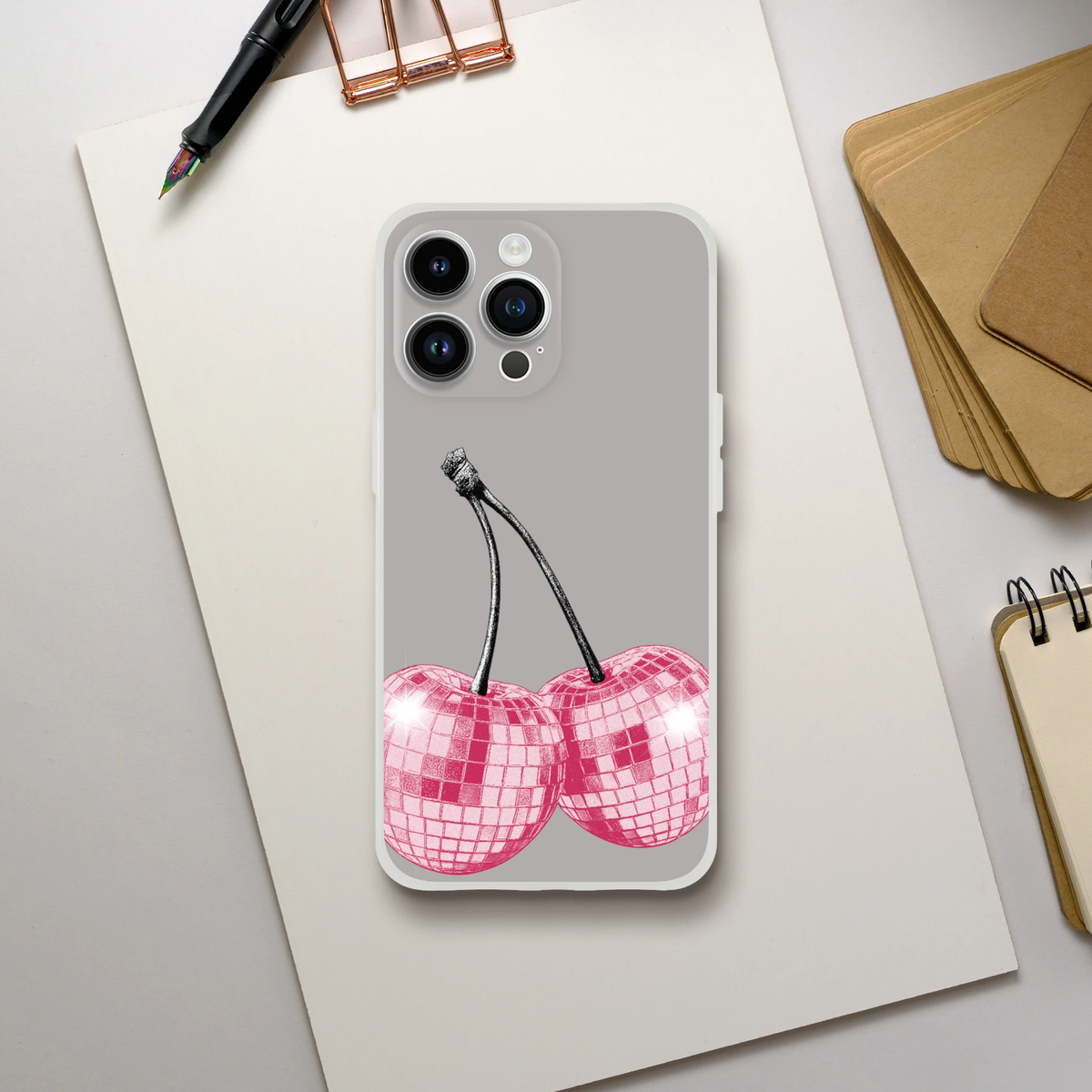 Y2K Glitter Cherries iPhone Case (13-16) retro aesthetic on a gray phone back with a desk setup