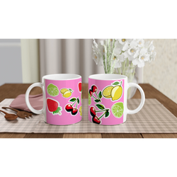 Pink ceramic mugs featuring cute stickers of cherries, lemons, limes, and strawberries on a wooden table.