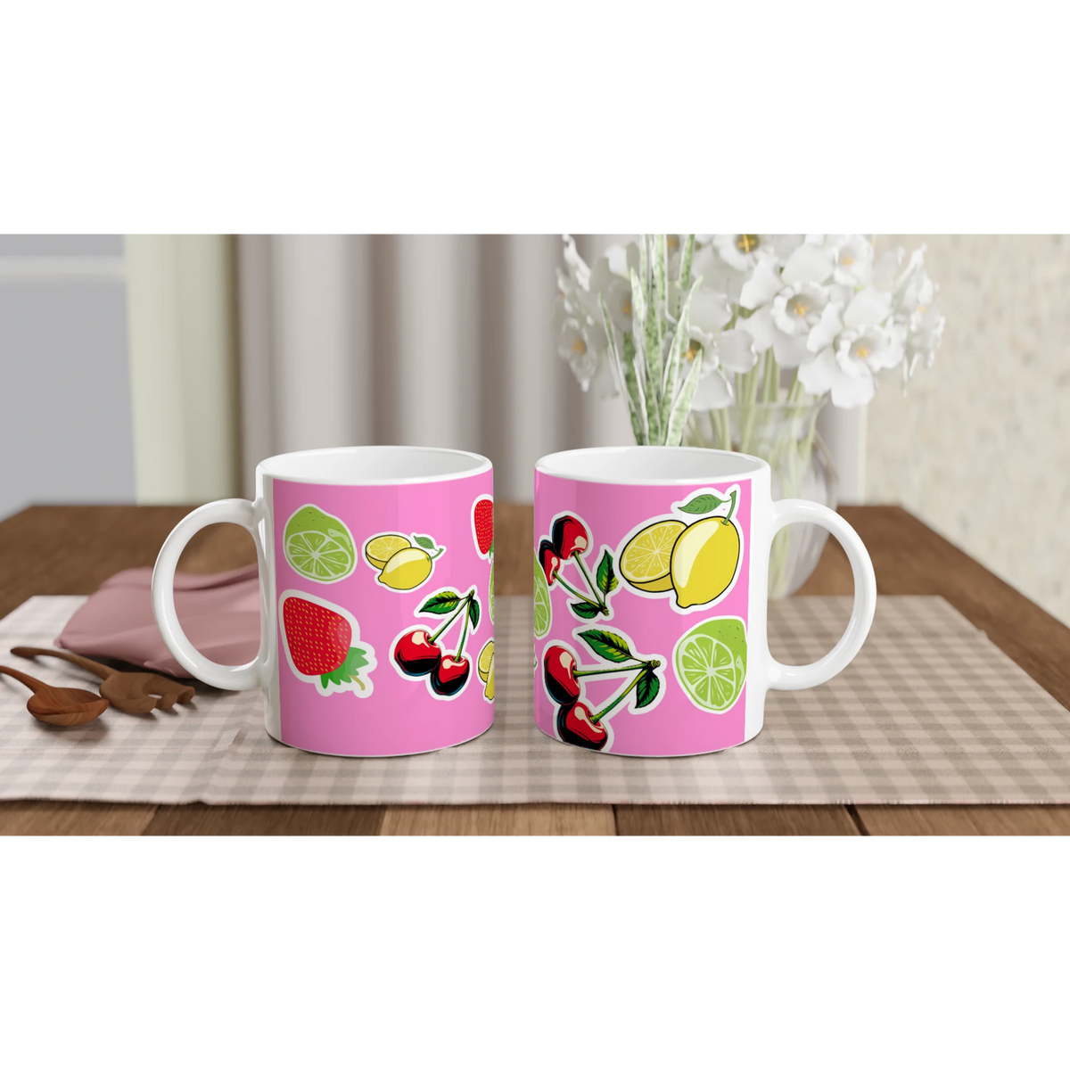 Pink ceramic mugs featuring cute stickers of cherries, lemons, limes, and strawberries on a wooden table.