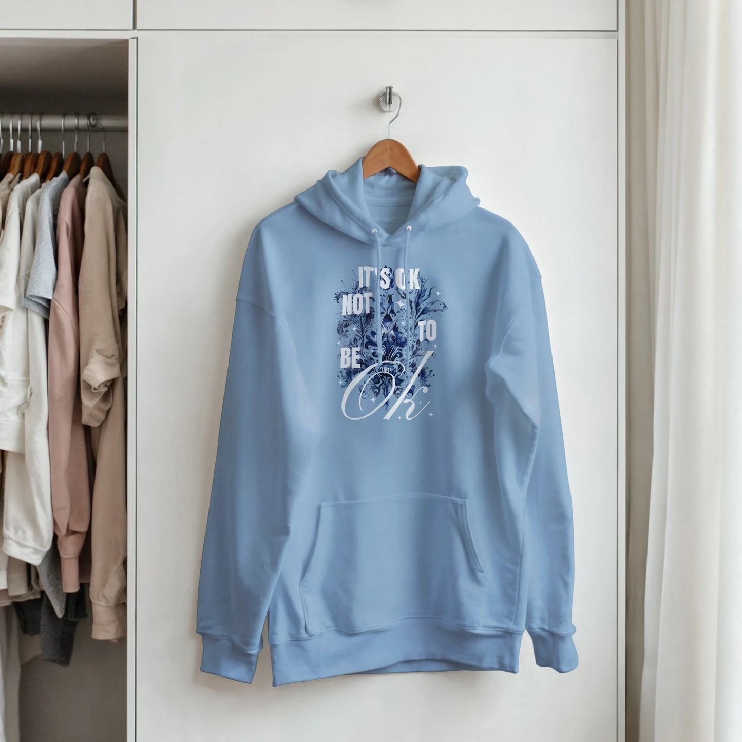 Light blue 50/50 cotton-poly hoodie with 'It's OK Not To Be OK' graphic, front pouch pocket, drawstring hood.