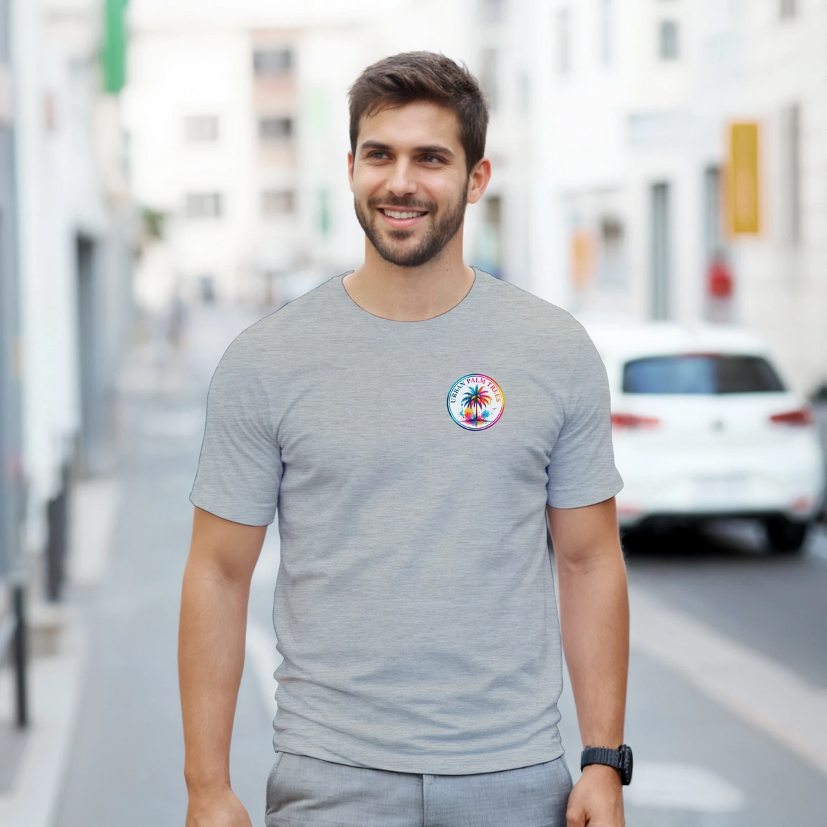 Man wearing grey crew neck tee with colorful Urban Palm Trees circular graphic on chest. Retro music style shirt.