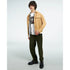 Male model in white Geisha Girl graphic T-shirt under tan jacket, olive pants, black shoes.