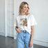 Woman wearing Tequila graphic T-shirt in white, casual crew-neck tee with retro tequila print and light wash jeans.