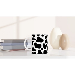 Black & white cow-print ceramic mug, a cute Y2K animal print coffee cup on a desk.