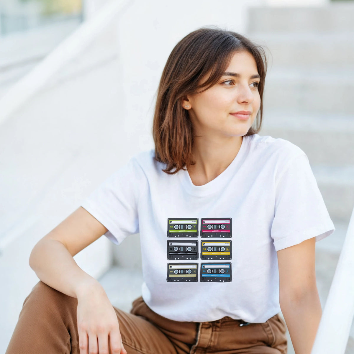 White crop top featuring a grid of six colorful retro cassette tapes. 80s music aesthetic gift for women.