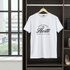 White t-shirt with 'Hustle' text on a hanger in a room with a window.