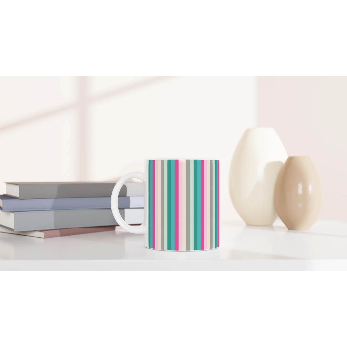 Pastel rainbow striped ceramic mug on a white desk with books and decor.