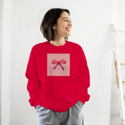 Woman wearing a red coquette aesthetic sweatshirt featuring a pink gingham square and satin bow graphic on the front.