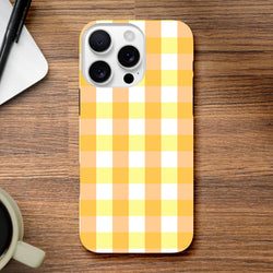 Retro yellow gingham checkered iPhone case on wooden desk. Cute protective cover featuring a bold orange, yellow, and white wraparound grid pattern for urban style.