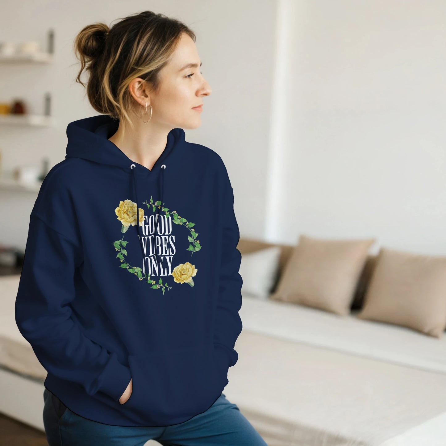 Woman in navy Good Vibes Only graphic hoodie with floral wreath, yellow flowers, front pouch pocket.