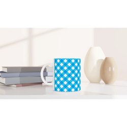 Blue checkered ceramic mug with white handle on a desk beside books and decor.