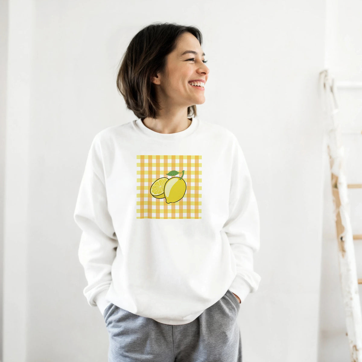 White sweatshirt featuring a retro yellow gingham square graphic with whole and sliced lemons.
