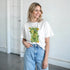 White Lemons women's graphic T-shirt with sunny lemon can print, soft cotton blend, worn by smiling model.