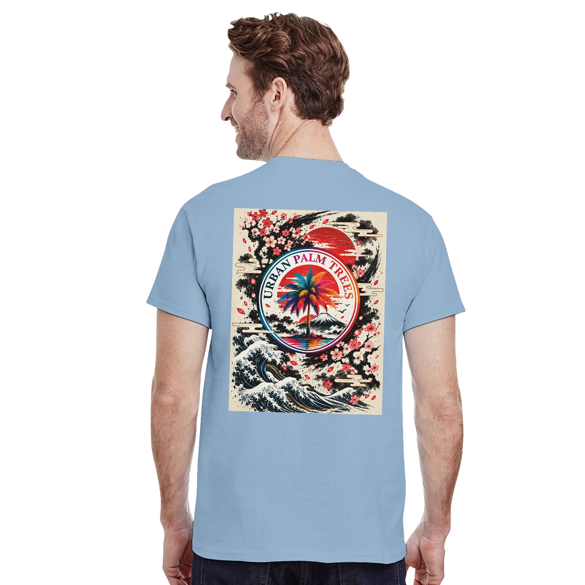 Man wearing light blue tee featuring retro Japanese wave back print with Mount Fuji, palm tree, and cherry blossoms.