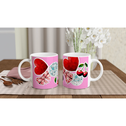 Cute coquette ceramic mug featuring pink bows, red hearts, cherries, and disco balls on a wooden desk.