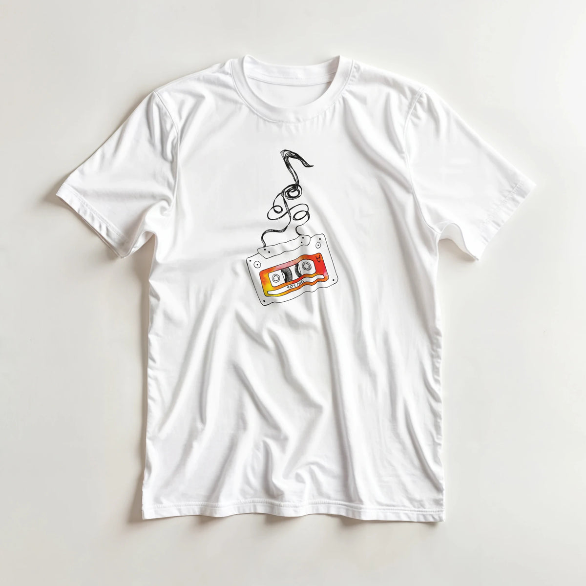 White t-shirt featuring a vintage cassette tape with unspooling tape and vibrant orange label, embodying retro music aesthetic streetwear.