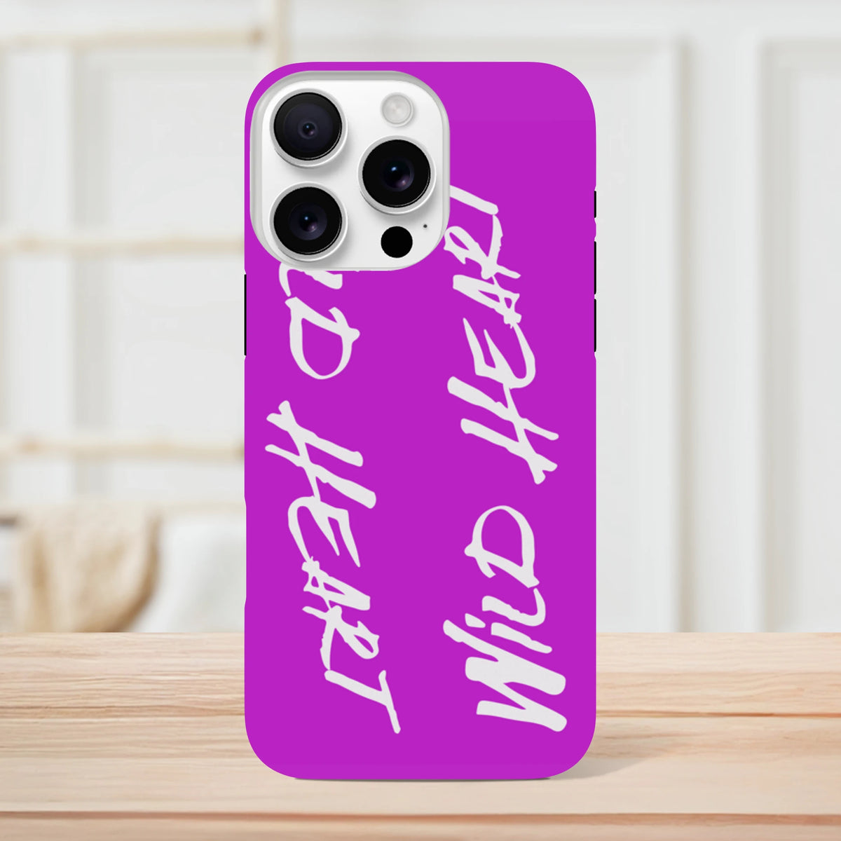 Vivid purple iPhone case featuring vertical white "Wild Heart" brush letter slogan text for streetwear style and tough protection.