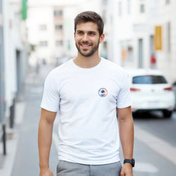 Smiling man in a white vintage palm tree graphic T-shirt with a circular chest logo in an urban street