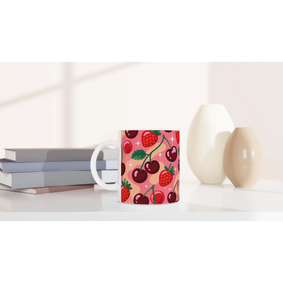 Retro cherry and strawberry pattern ceramic mug on a white desk beside books and vases.
