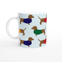 Sausage dog ceramic mug with dachshund pattern and colorful sweaters on a light blue striped background.