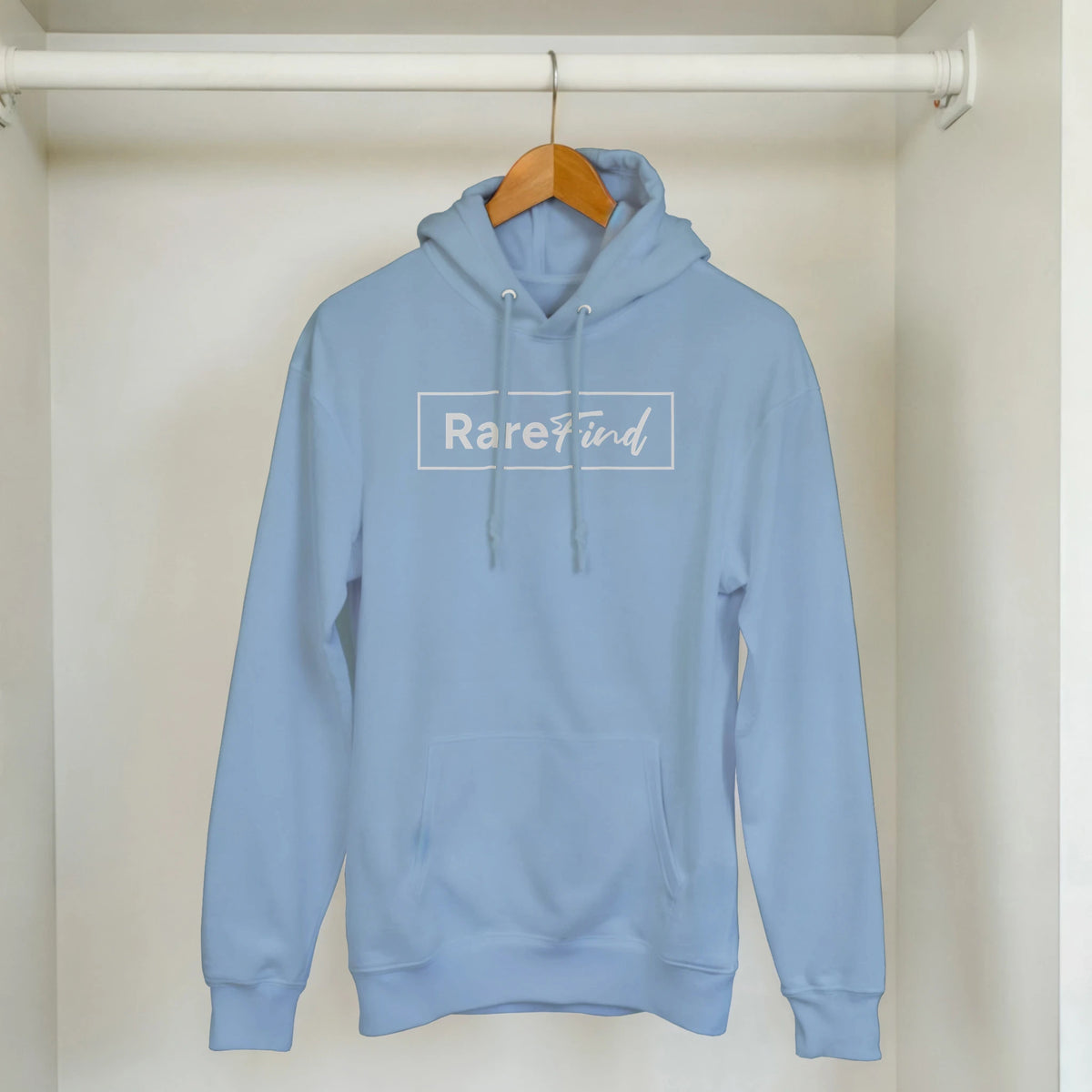 Light blue hoodie on a wooden hanger in a closet, featuring Rare Find logo on the chest and front pouch pocket.