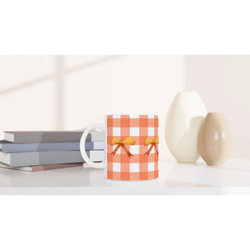 Orange gingham bow mug with white handle and bow accent, placed on a desk beside stacked books.