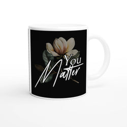 White ceramic mug with black wraparound print featuring a magnolia flower and You Matter slogan.