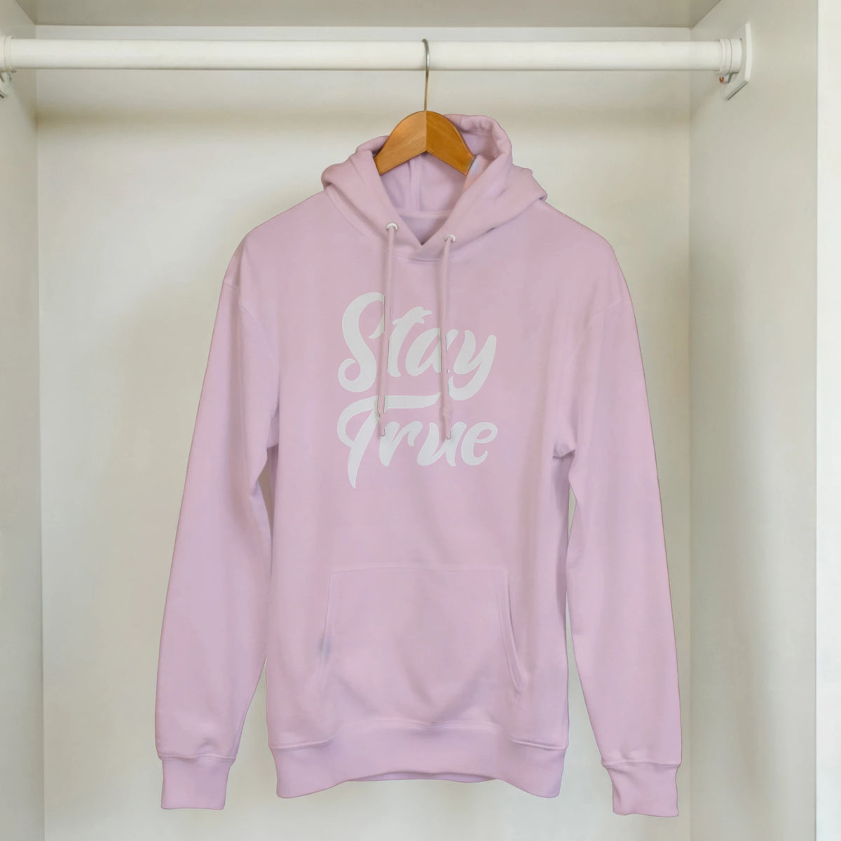 Cute Stay True Hoodie in pastel pink on a hanger, white Stay True slogan across the chest.