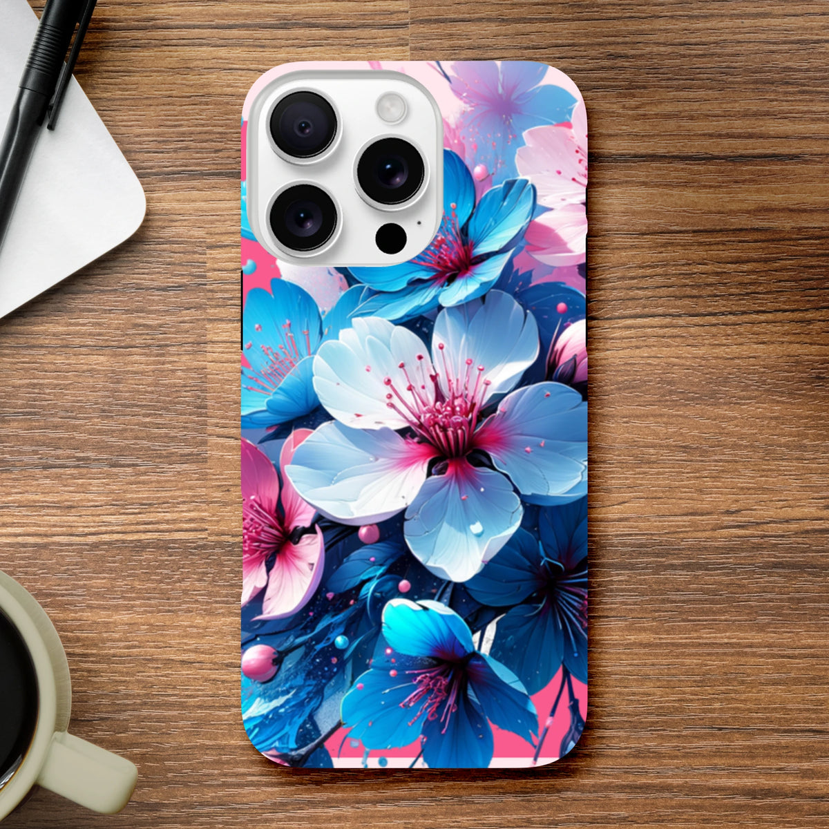 Vibrant blue and pink floral iPhone case on a wooden desk beside a coffee cup and pen.