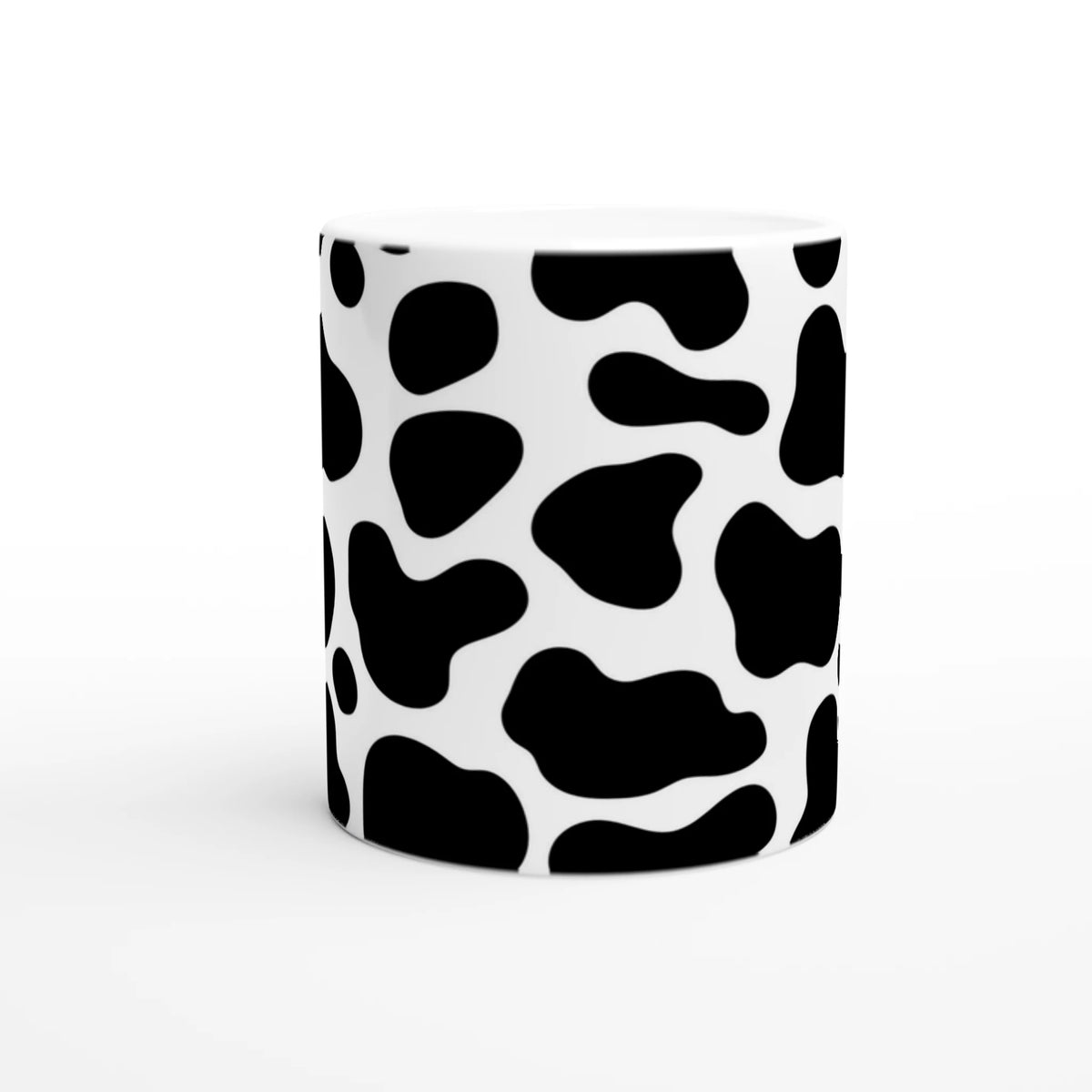 White ceramic mug with bold black cow-print pattern, a cute Y2K animal-print coffee cup.