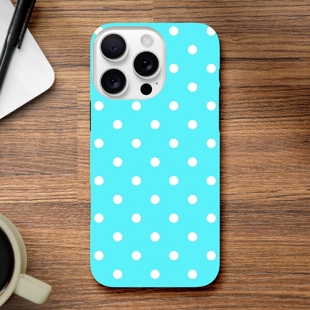 Turquoise & white polka dot tough iPhone case with glossy finish and drop protection on wooden desk.