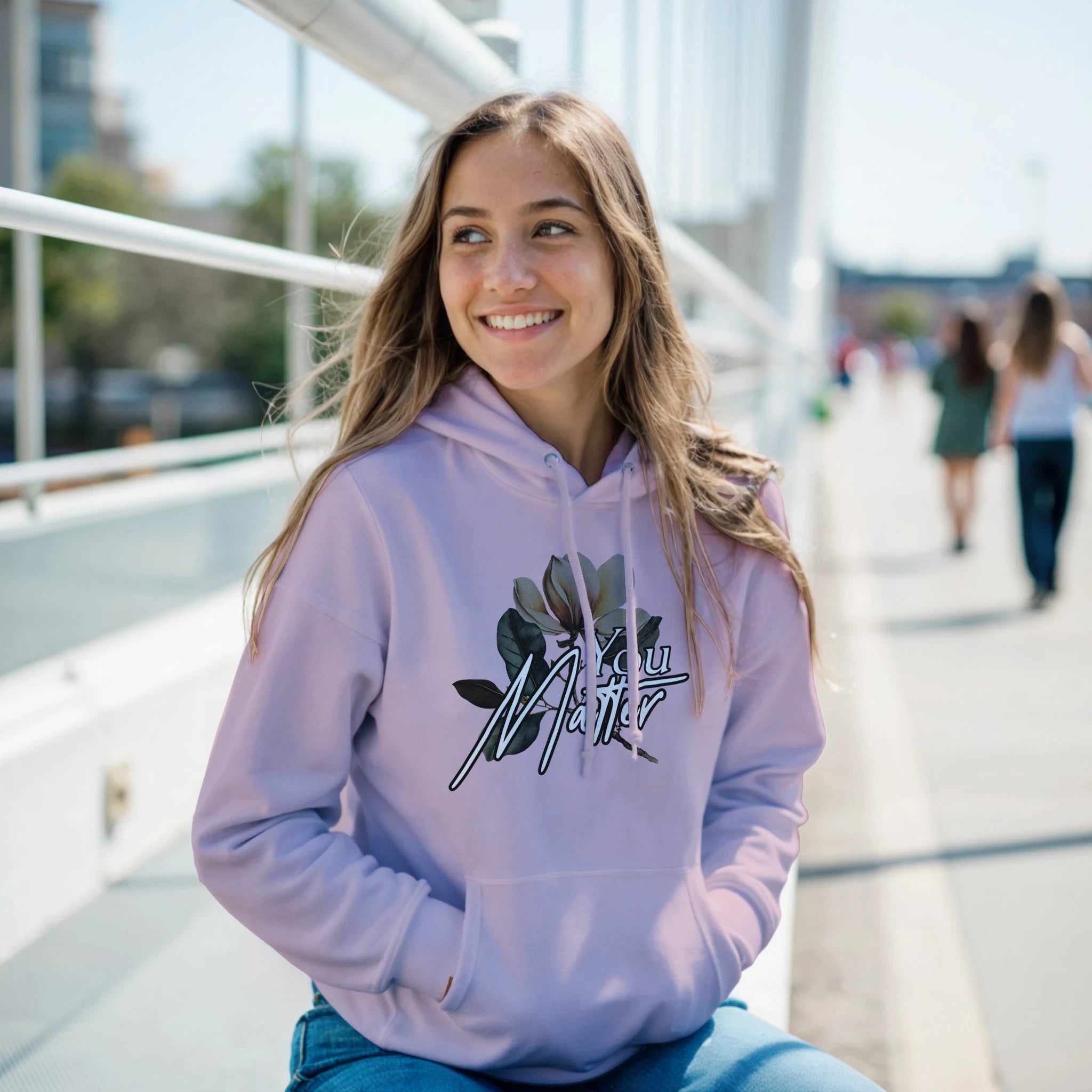 Woman wearing lavender You Matter slogan hoodie with floral graphic and front pocket; soft cotton blend.