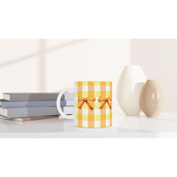 Yellow gingham bow mug on a white desk with gift boxes nearby.