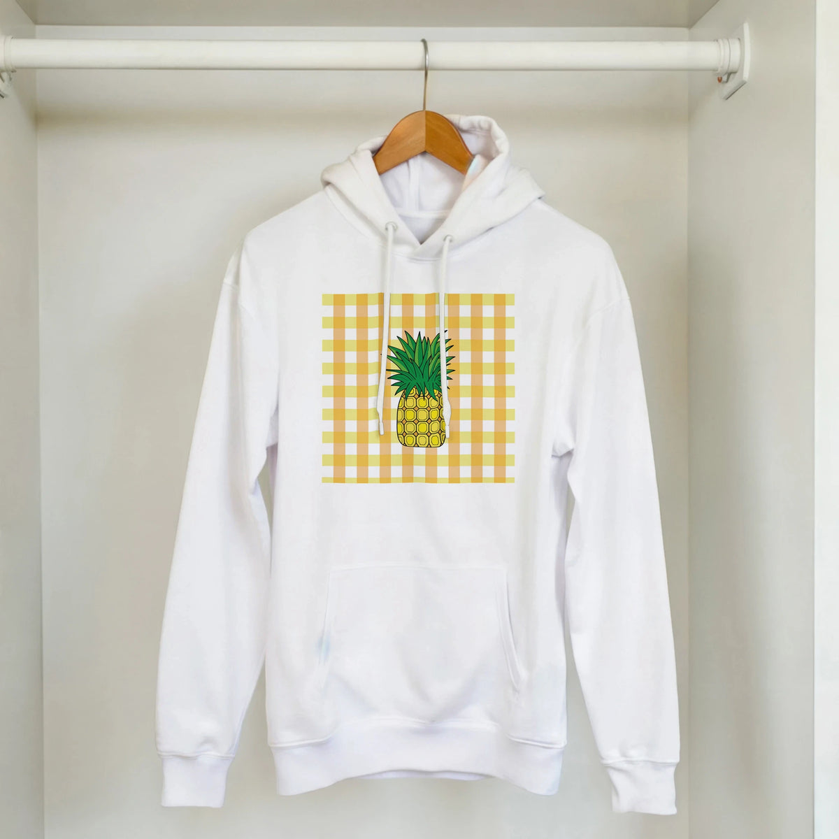 White pullover hoodie featuring a retro yellow gingham square and vintage pineapple graphic on the front.