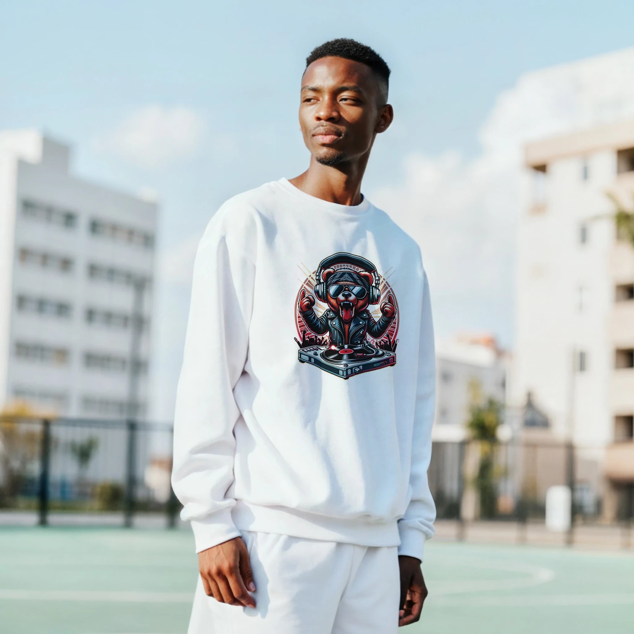 Man in white teddy bear graphic sweatshirt with headphones outdoors.