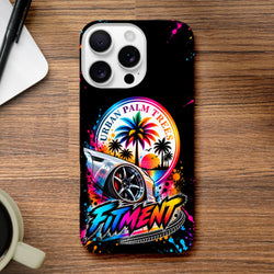 Black iPhone case featuring a colorful lowered modified car, vibrant "Urban Palm Trees" sunset graphic, and bold "Fitment" lettering with paint splatters.