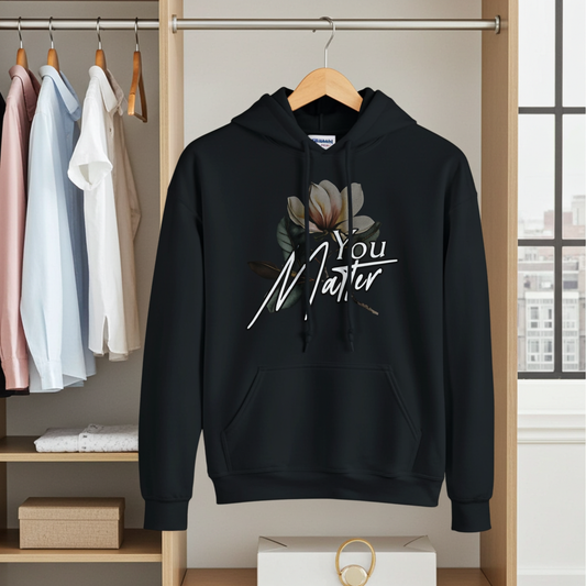 Black hoodie with floral design and text hanging on a rack in a clothing store.