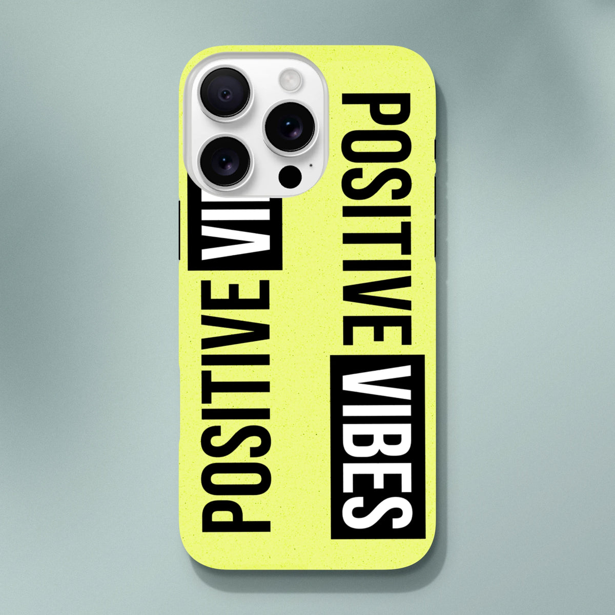 Bright yellow iPhone case featuring bold "POSITIVE VIBES" slogan text in black and white wraparound print for tough streetwear protection.