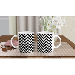 Pair of black and white herringbone ceramic mugs with geometric chevron design on a checkered placemat.