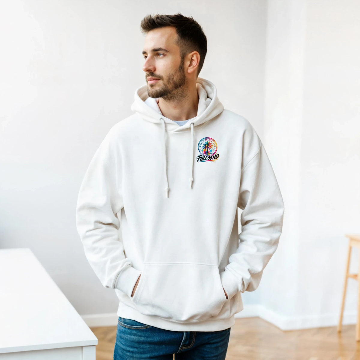 Man wearing white Full Send streetwear hoodie with colorful palm tree graphic, paired with blue jeans for a relaxed daily look.