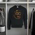 Black sweatshirt with bear graphic on a hanger in a wardrobe.