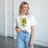 Model wearing white Lemons graphic T-shirt with yellow lemon illustration, paired with light blue jeans.