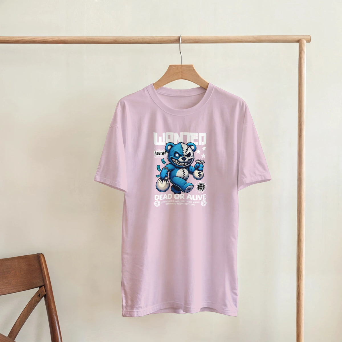Pink men's graphic T-shirt with a blue teddy bear illustration and 'Wanted Dead or Alive' motif.