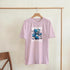Pink men's graphic T-shirt with a blue teddy bear illustration and 'Wanted Dead or Alive' motif.