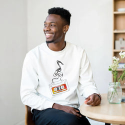 White crewneck sweatshirt featuring a retro cassette tape graphic with unspooling tape and 90s Hits text design.